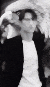 a blurry black and white photo of a man wearing a white shirt and a black jacket