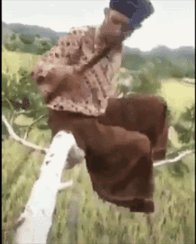 a man is sitting on a tree branch with his legs crossed .