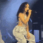 a woman with curly hair is singing into a microphone on a stage
