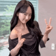 a young woman is giving a peace sign with her hands .