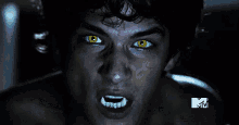 a close up of a man 's face with yellow eyes and a mtv logo in the background