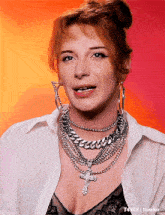 a woman wearing a necklace with a cross on it and hoop earrings