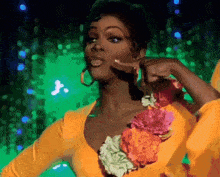 a woman in a yellow top with flowers on it is pointing