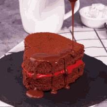 a slice of chocolate cake with red frosting is being drizzled with chocolate