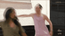 a woman in a pink dress is dancing with another woman in a green shirt .