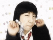 a young boy in a school uniform is making a funny face while holding something in his hands .
