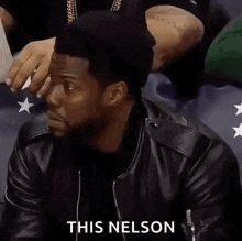a man in a leather jacket is sitting in a stadium with the words alright then this nelson on the bottom .