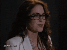 a woman wearing glasses and a white jacket is smiling with the hashtag lialmeida05 below her