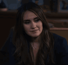a woman wearing a blue jacket and a necklace with the letter o on it
