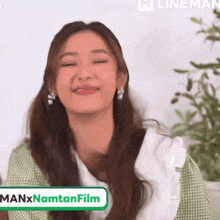 a woman in a green and white dress is smiling with her eyes closed