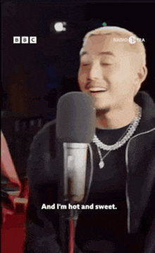 a man is singing into a microphone and saying and i 'm hot and sweet