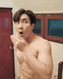a shirtless man is making a funny face while standing in front of a window .