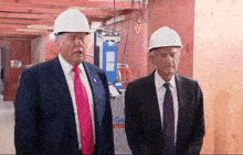 two men wearing hard hats are standing in front of a sign that says go 2703