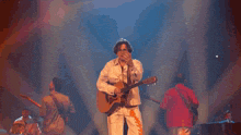 a man playing a guitar on a stage with other people