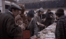 a group of people are standing around a long table with food on it