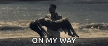 a man is holding a woman in his arms on the beach .
