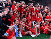 a group of soccer players are posing for a photo with a trophy and a shirt that says standard chartered on it