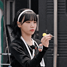 a girl wearing a headband and a lanyard is holding a dart