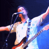 a man is singing into a microphone while playing a guitar