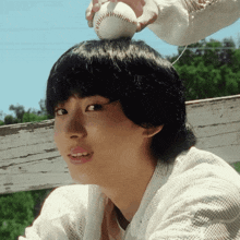 a person holding a baseball on a woman 's head
