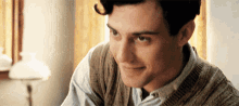 a close up of a man wearing a sweater and a blue shirt