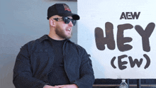 a man stands in front of a sign that says hey