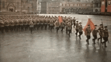 a blurred image of soldiers marching in a line with one holding a red flag