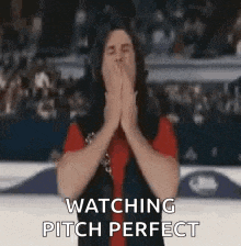 a man is covering his mouth with his hands and saying `` watching pitch perfect '' .