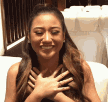 a woman with her hands on her chest is smiling .