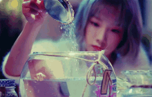 a woman is pouring water into a fish bowl with a label that says ' ts kamii ' on it
