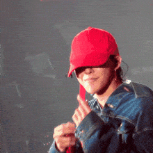 a man wearing a red hat and a denim jacket is giving a thumbs up