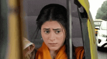 a woman is looking out the window of a yellow car .