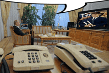 a man sits in a chair in front of a television with a speech bubble behind him