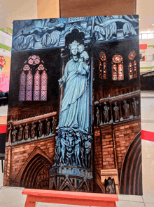 a painting of a statue of a woman holding a baby is on display in front of a sign that says din