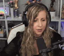 a woman wearing headphones is talking into a microphone with a sign on the shelf that says " welcome "