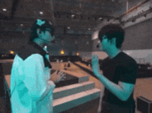 two men are standing next to each other in a room talking to each other .