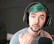 a man with green hair wearing headphones and a microphone .