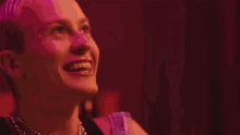 a woman with a tattoo on her face is smiling and wearing a chain around her neck