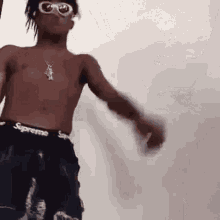 a shirtless young man wearing sunglasses and supreme underwear is dancing .