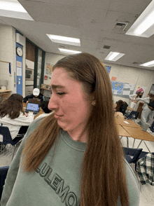 a girl wearing a lululemon sweatshirt makes a funny face in a classroom