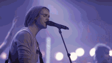 a man singing into a microphone with a crowd behind him