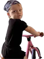 a baby wearing a bandana is riding a pink bicycle