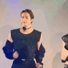 a man in a black dress is dancing on a stage with a microphone in his ear .