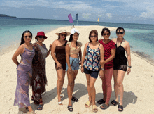 a group of women are posing for a picture on a sandy beach