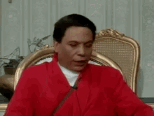 a man in a red robe is sitting in a chair with his mouth open .