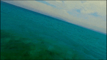 a picture of a turquoise ocean with a cloudy sky in the background