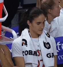a woman wearing a white shirt that says foras on it