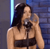 a woman is drinking water from a glass while standing in front of a microphone .