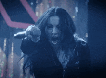 a woman is singing into a microphone and pointing