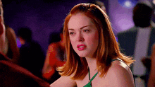 a woman with red hair is wearing a green top and lipstick